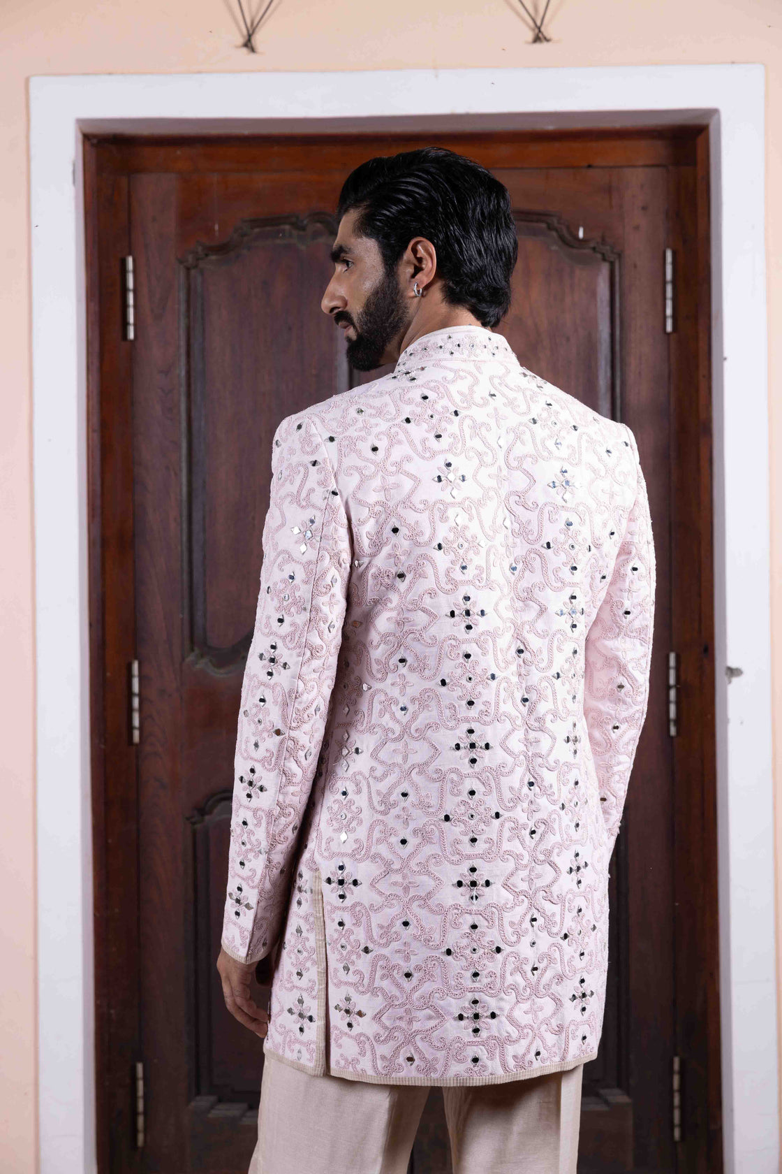 Soft pink tussar silk long jacket with mughal jali inspired resham, kasab and mirror work paired with ivory textured tissue sleeveless button bundi and flared pant Nafsstore